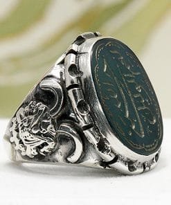 Yeşil Akik Taşlı Hasbinallah Ve Nimel Vekil Yazılı El Yapımı Yüzük, oval koyu yeşil akik, Arapça hat ve kenarlarında süslü hilal motifleri bulunan el yapımı gümüş bir yüzüktür.